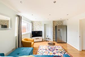 a living room with a blue couch and a television at Overbury Lodge, Birmingham with FREE Parking in Northfield