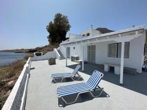 2 sillas sentadas en un patio junto a una casa en Santorini Grace Villa 3 en Foinikiá