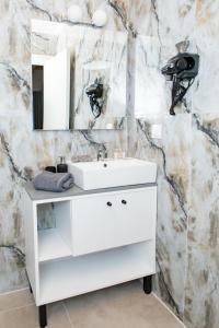 a bathroom with a white sink and a mirror at Four Princess in Agia Paraskevi