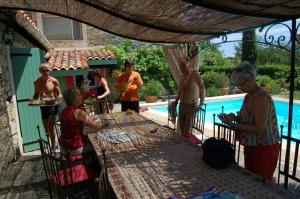 a group of people standing around a table next to a pool at La Picholine, chambre ciboulette in Courry