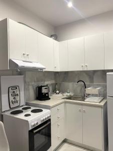 a kitchen with white cabinets and a stove top oven at Aggelikas apartments in Paleokastritsa
