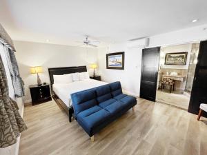 Catalina Courtyard Suites في أفالون: غرفة نوم بسرير واريكة زرقاء