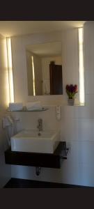 a bathroom with a white sink and a mirror at Self CheckIn Hotel Heckenrose Lorin in Ringsheim