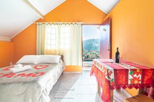 um quarto com uma cama, uma mesa e uma janela em Chales Fazenda Cantinho do Selado em Monte Verde