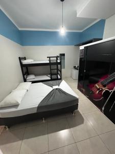 ein Schlafzimmer mit einem Bett mit einer Gitarre an der Wand in der Unterkunft Pousada Vitória Régia Olímpia in Olímpia