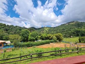 uma vista para uma quinta com montanhas ao fundo em Chales Fazenda Cantinho do Selado em Monte Verde