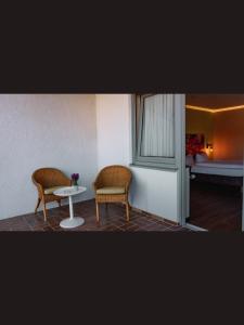 a room with two chairs and a table and a bed at Self CheckIn Hotel Heckenrose Lorin in Ringsheim