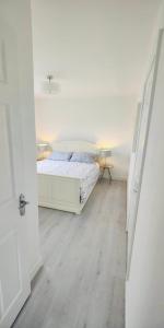 a white bedroom with a bed and a wooden floor at The Bay house in Derry Londonderry