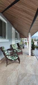3 chaises et une table sur une terrasse couverte dans l'établissement Pousada Kaki Haus, à Pomerode