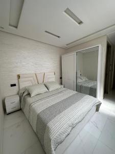een witte slaapkamer met een groot bed en een spiegel bij اقامة الانوار in Nador