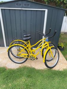uma bicicleta amarela estacionada na relva ao lado de uma garagem em BEE LOCAL LABHOUSE em Fare