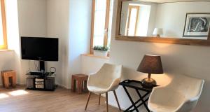 - un salon avec deux chaises blanches et une télévision dans l'établissement Dorf Hotel "Zuhause in Lachen", à Lachen