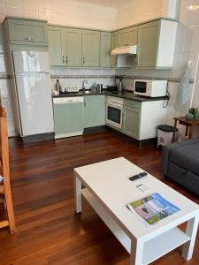 een keuken met groene kasten en een witte salontafel bij Viviendas Turísticas Los Cubos de Llanes 3 in Llanes