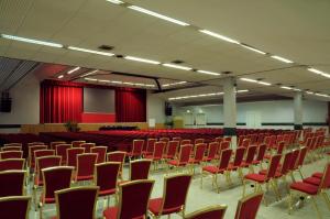 an empty room with red chairs and red curtains at Hotel Alexander Business and Conference in Abano Terme