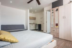 un dormitorio blanco con una cama y una cocina en Iris Studios & Apartments, en Playa del Carmen