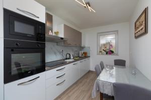 a kitchen with white cabinets and a black microwave at Apartments with parking space Stanici, Omis - 11421 in Celina