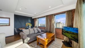 a living room with a couch and a tv at Central City View with Free Valet Parking in Christchurch