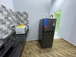 La cuisine est équipée d'un réfrigérateur noir et d'un four micro-ondes. dans l'établissement Homestay 4S, à Marang
