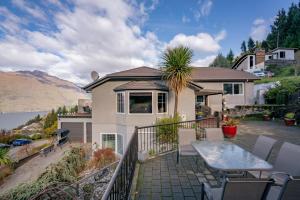 a house with a balcony with a table and chairs at Awesomely Wakatipu Queenstown Home in Queenstown