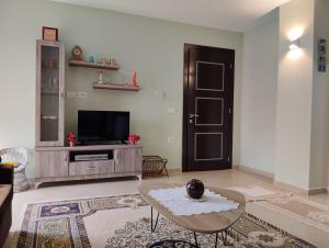 sala de estar con TV, mesa y puerta en Dhoma romantike , qetesi absolute!, en Korçë
