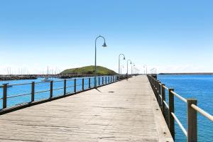a wooden pier with street lights on the water at Serenity Bay Studio in Coffs Harbour