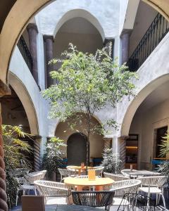 a courtyard with tables and chairs and a tree at Casa Maka in San Luis Potosí