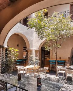 un restaurante con mesas, sillas y un árbol en Casa Maka en San Luis Potosí