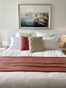 a white bed with pillows and a painting on the wall at Waterfront Sub-Penthouse with Beach View in Geelong