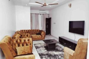 a living room with two couches and a flat screen tv at Cityflats Apartment in Owerri