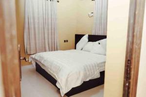 1 dormitorio con 1 cama con sábanas y almohadas blancas en Cityflats Apartment, en Owerri