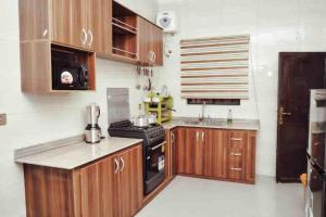 a kitchen with wooden cabinets and a stove top oven at Cityflats Apartment in Owerri