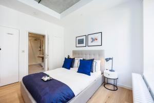 ein weißes Schlafzimmer mit einem großen Bett mit blauen Kissen in der Unterkunft Apartment Near Canary Wharf 02 Arena & Excel in London