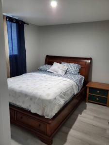 a bedroom with a bed with a wooden frame and a table at Lovely Suite 2 Bedrooms in Airdrie