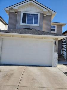 a white garage door in front of a house at Lovely Suite 2 Bedrooms in Airdrie