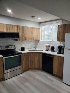 a kitchen with wooden cabinets and a stove top oven at Lovely Suite 2 Bedrooms in Airdrie