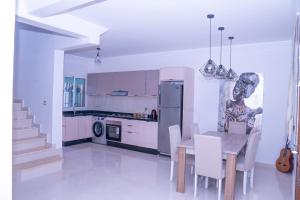 a kitchen and dining room with a table and a refrigerator at Duplex La roseraie à 2min de la plage 2 piscines in Sidi Bouzid