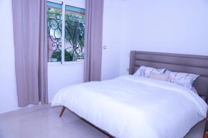 a bedroom with a white bed with a window at Duplex La rose neuf et elegant in Sidi Bouzid