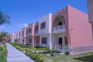 a pink building with a pathway in front of it at Duplex La rose neuf et elegant in Sidi Bouzid