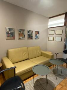 a living room with a yellow couch and two tables at Jardim do Morro Places in Vila Nova de Gaia