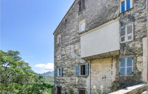 an old stone building with blue and white windows at Cozy Apartment In Ghisoni With Kitchen in Ghisoni