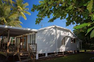 een wit tiny house met een veranda en een palmboom bij Bev's on the Beach - Absolute Beachfront Cottage in Mission Beach