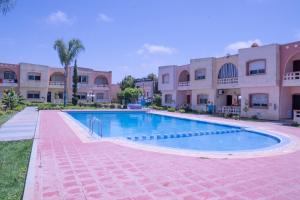 a swimming pool in front of a building at Duplex La roseraie à 2min de la plage 2 piscines in Sidi Bouzid