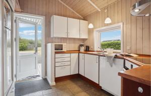 Una cocina con gabinetes blancos y una ventana grande. en Holiday Home Sydmarken Hemmet Ii, en Falen