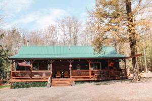 a log cabin with a green roof and an american flag at Mountain-Top-Hideaway Stay in a log cabin on a private rd! Swim, hike, explore a true mountain experience in North Blenheim