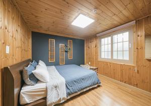 - une chambre avec un lit dans une pièce dotée de murs en bois dans l'établissement Jeju Haepoomdal Pension, à Jeju