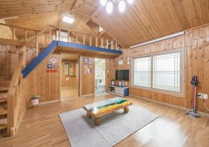 Cette grande chambre est dotée de murs en bois et d'un escalier bleu. dans l'établissement Jeju Haepoomdal Pension, à Jeju