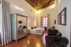 a bedroom with a bed and a mirror and a chair at Palacio Pinello in Seville