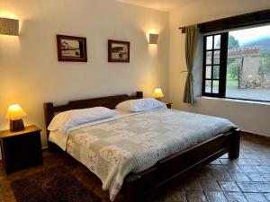 a bedroom with a bed with two lamps and a window at Hacienda Veracruz villa de leyva in Villa de Leyva