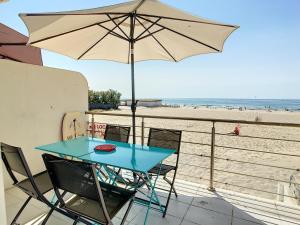 - une table et des chaises avec un parasol sur la plage dans l'établissement Appartement Palavas-les-Flots, 2 pièces, 4 personnes - FR-1-715-62, à Palavas-les-Flots