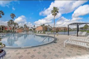 a swimming pool with white chairs and a patio at Cozy & spacious 2 BR / 2 BA condo in Kissimmee